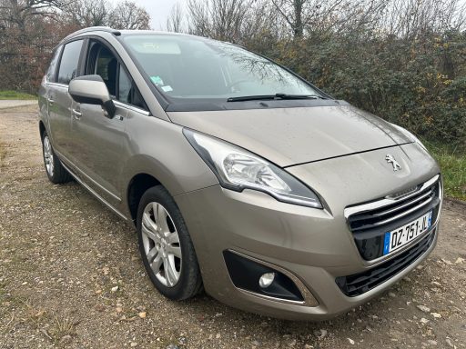 Voiture compacte Peugeot sur une route gravillonnée, couleur gris clair.